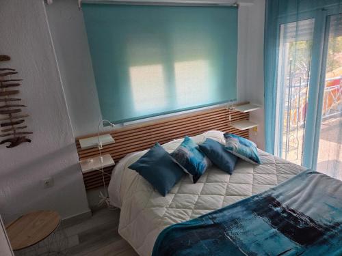 a bedroom with a bed with blue pillows and a window at Aura in Gerakini