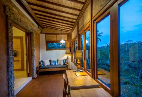 a room with a table and a bed and large windows at Ulun Ubud Resort - CHSE Certified in Ubud