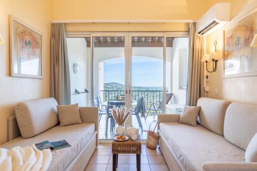 a living room with a couch and a balcony at Résidence Pierre & Vacances Les Restanques du Golfe de Saint-Tropez in Grimaud