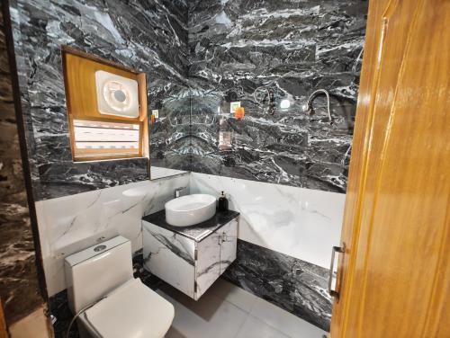 a black and white bathroom with a toilet and a sink at Rudra BNBF in Gandhidham
