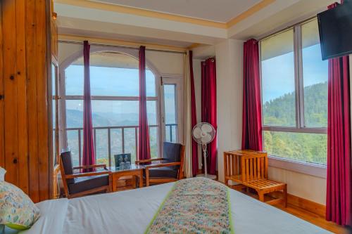 a bedroom with a bed and a desk and windows at Mashobra Heights By shrpl in Kīar