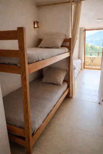 a room with four bunk beds with a balcony at Vue montagne exceptionnelle T2 Cosy avec Balcon proche du lac in Embrun