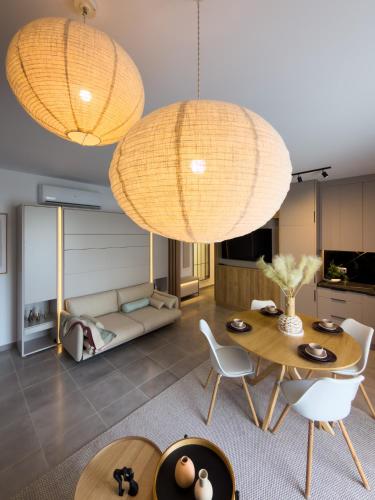 a living room with two chandeliers and a table and chairs at The Calaya - Aparthotel Saranda in Sarandë