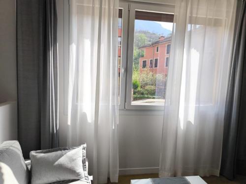 a room with a window with white curtains and a couch at Apartamento La Mandrágora in Arenas de Cabrales