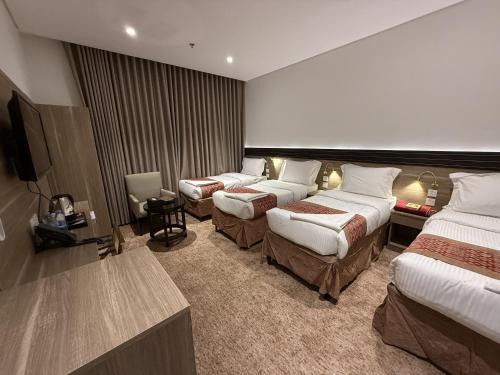 a hotel room with three beds and a flat screen tv at Retaj Al Noor Hotel, فندق ريتاج النور in Medina