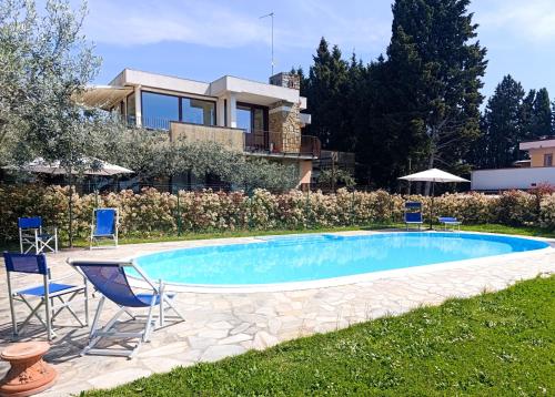 a swimming pool with chairs and a house at Appartamento con piscina in Villa in Florence