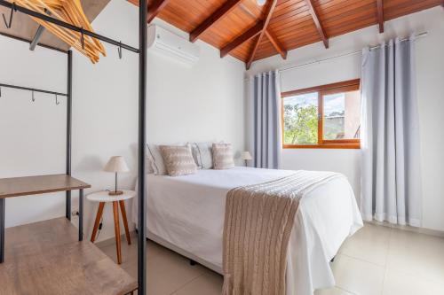 a white bedroom with a bed and a window at Cerrado Ville in Alto Paraíso de Goiás