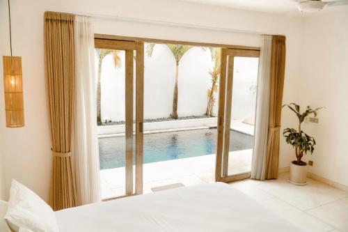 a bedroom with a swimming pool seen through a window at Casa Solisa in Kerobokan