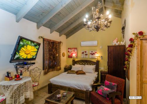 a bedroom with a bed and a tv and a chandelier at Zemer Lodging in Sede Eli‘ezer