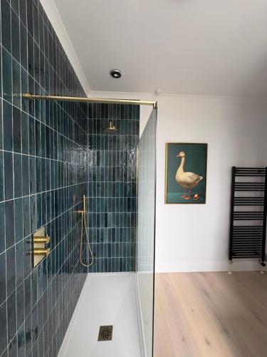 a bathroom with a shower and a painting of a duck on the wall at Trevanger Farm Bed and Breakfast in Wadebridge