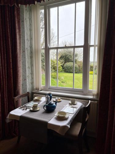 a table in front of a window with a table and chairs at Trevanger Farm Bed and Breakfast in Wadebridge