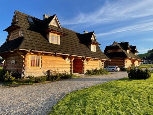 a large wooden house with a gambrel roof at Sun&Ski Maciejówka Domki Białka Tatrzańska in Białka Tatrzańska