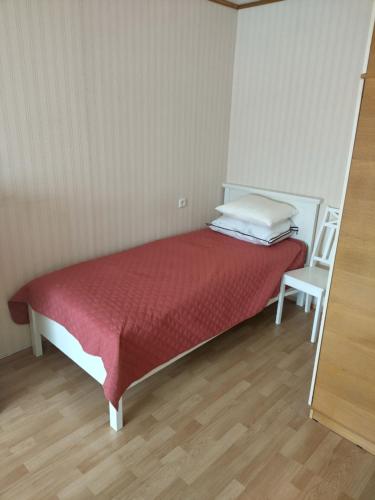 a bedroom with a bed with a red blanket and a chair at Retrokodu in Rakvere