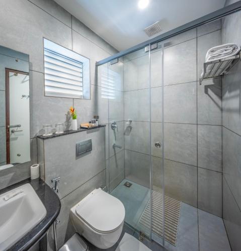 a bathroom with a shower and a toilet and a sink at Blanket Riverside Resort and Spa in Munnar