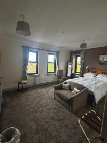 a bedroom with a bed and a couch and windows at The Greannan Bed & Breakfast in Blackwaterfoot