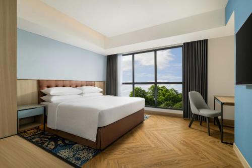 a bedroom with a bed and a desk and a window at Four Points by Sheraton Pontianak in Pontianak