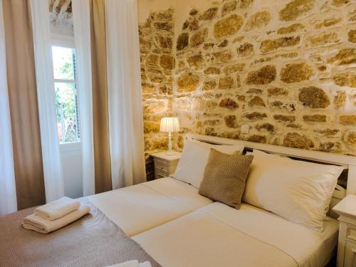 a bedroom with a white bed with a stone wall at Spiti Mata in Perítheia