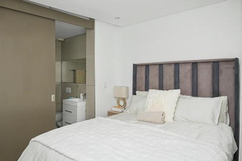 a bedroom with a large white bed with a wooden headboard at Casa Solis at Wild Olive in Windhoek