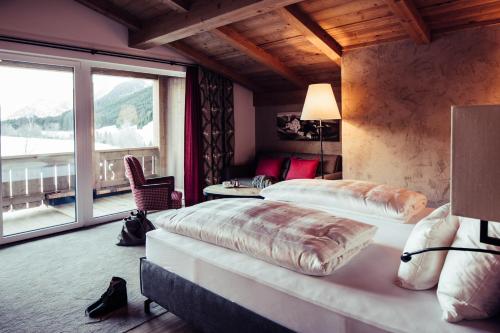 une chambre avec deux lits et une grande fenêtre dans l'établissement Biohotel Bergzeit, à Zöblen