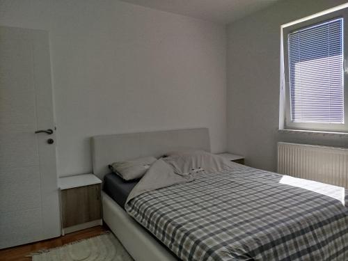 a bedroom with a bed with a checkered blanket and a window at Smjestaj_S in Bijeljina
