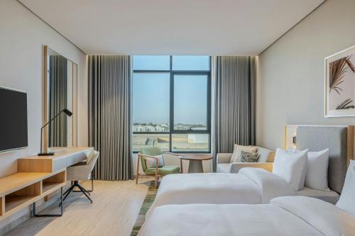 a hotel room with two beds and a desk at Element by Marriott Al Qassim in Buraydah