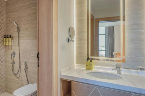 a bathroom with a sink and a toilet and a mirror at Element by Marriott Al Qassim in Buraydah