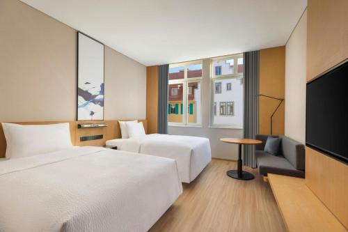 a hotel room with two beds and a flat screen tv at Fairfield by Marriott Hengdian in Dongyang