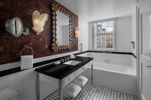 a bathroom with a tub and a sink and a mirror at The Stoneleigh, Autograph Collection in Dallas