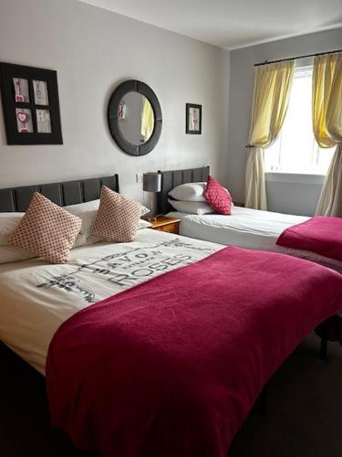 a bedroom with two beds with red blankets and a mirror at Dunroamin Self-Catering Apartment in Aviemore