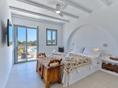 a white bedroom with a bed and a window at Villa Katy in Aspro Chorio Paros