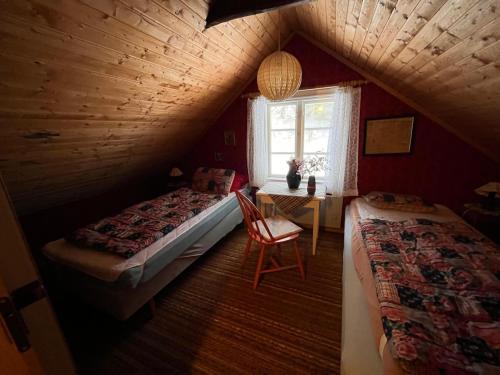 a attic bedroom with two beds and a chair at Cozy farmhouse with rowboat! in Skönberga