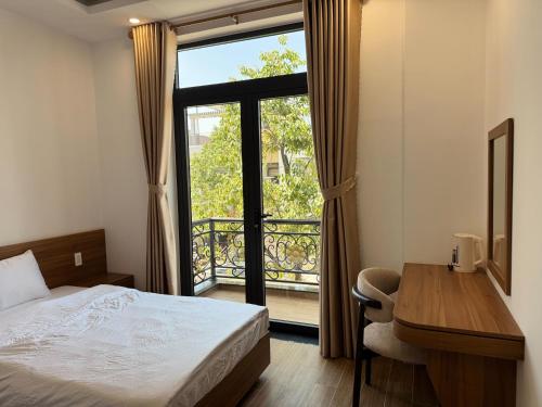 a bedroom with a bed and a desk and a window at Khách sạn Lâm Hà - Laha Hotel in Riong Serignac