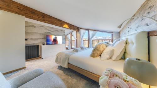 a bedroom with a large bed and a tv at Luxury chalet - fireplace heated pool & sauna in Megève
