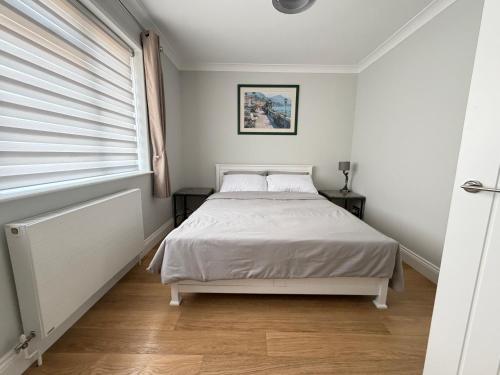 a white bedroom with a bed and a window at Teran the apartment in Timsbury