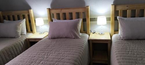 a bedroom with two beds and two lamps on tables at AMBROZIA Apartment-self catering-2bed2bath in Bloemfontein