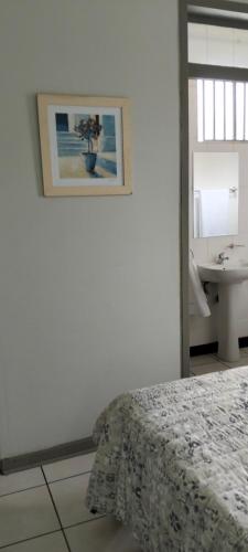 a bedroom with a bed and a bathroom with a sink at AMBROZIA Apartment-self catering-2bed2bath in Bloemfontein