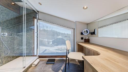 a bathroom with a glass shower and a desk and a chair at Luxury chalet - fireplace heated pool & sauna in Megève