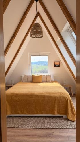 a bedroom with a large bed with a window at Designer chalet with gorgeous Eifel panorama in Kerschenbach