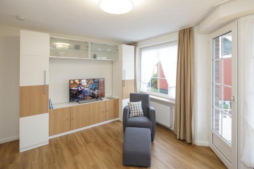 a living room with a tv and a chair at Haus Wattenblick in Cuxhaven