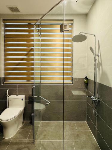 a bathroom with a toilet and a glass shower at Khách sạn Lâm Hà - Laha Hotel in Riong Serignac