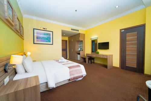 a hotel room with a large bed and yellow walls at HIG Hotel & Convention in Kuah