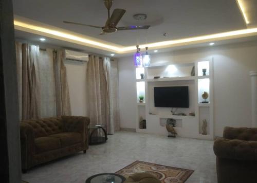 a living room with a couch and a flat screen tv at Modern Way Guesthouse in Kasoa