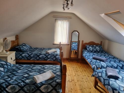 a attic bedroom with two beds and a mirror at Church View B&B in Ballycastle