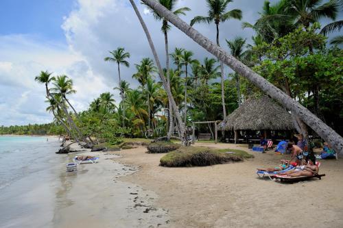 a group of people laying on a beach with palm trees at Hotel Atlantis in Las Terrenas