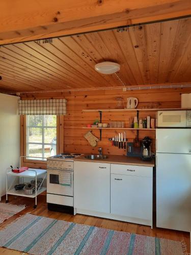 a kitchen with white appliances and a wooden ceiling at Mökki Katjukka, Ruka in Kuusamo