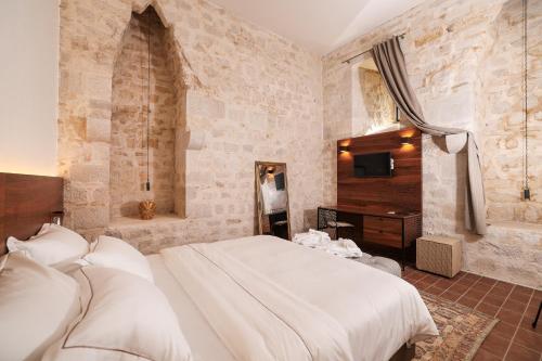 a bedroom with a bed and a desk and a television at Heritage Hotel Maskovica Han in Pakoštane