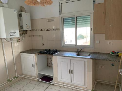 a kitchen with white cabinets and a sink and a window at honey moon zeinbe 4 in Hammamet