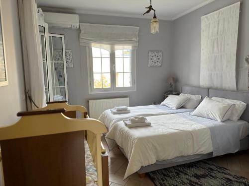 a bedroom with a bed with white sheets and a window at Chris Villa in Perdika