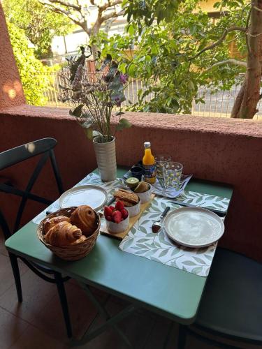 a table with plates of food and a basket of fruit at Appartement en résidence d'exception avec piscine dans le cap corse in Sisco