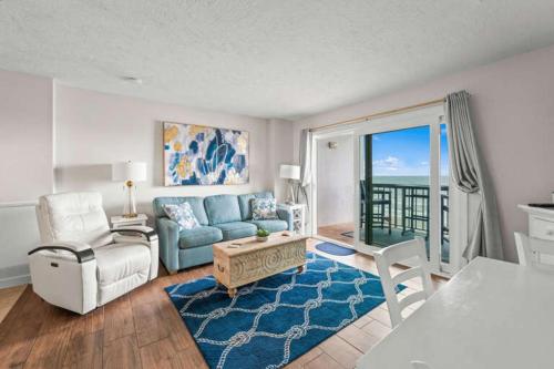 a living room with a blue couch and a table at Oceanfront Condo, Steps to the Beach in Myrtle Beach